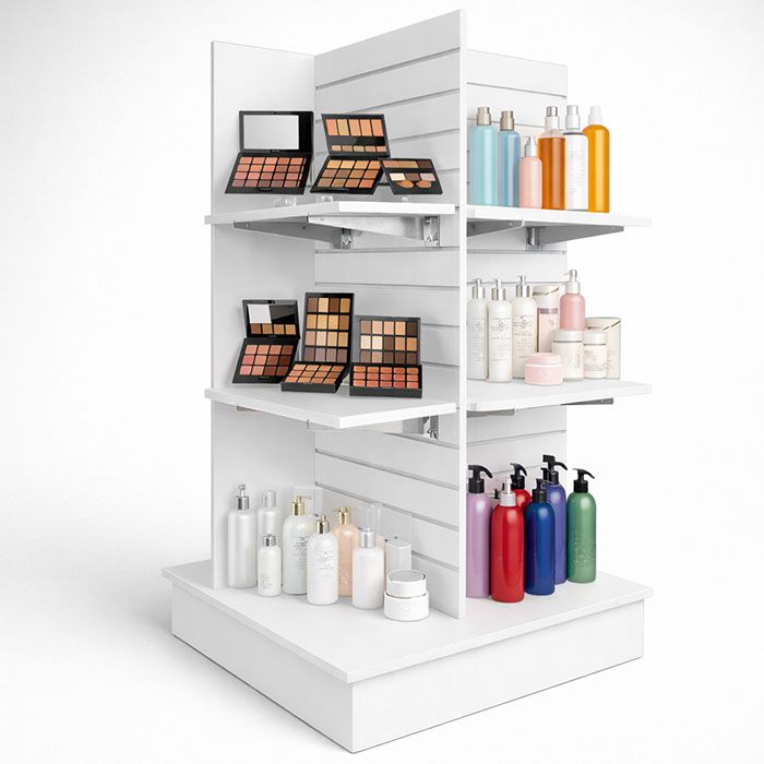 White 4-way pinwheel slatwall gondola display featuring beauty products, makeup palettes, and skincare bottles.