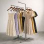 Bauhaus 4-way stainless steel clothing display rack featuring adjustable height straight arms showcasing floral dresses in a retail space.