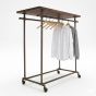A three-quarter view of a dark grey pipeline double-bar clothing rack featuring a dark wood top shelf, on casters.