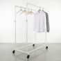 Boutique showroom display featuring white industrial pipe garment rack with double hang rails